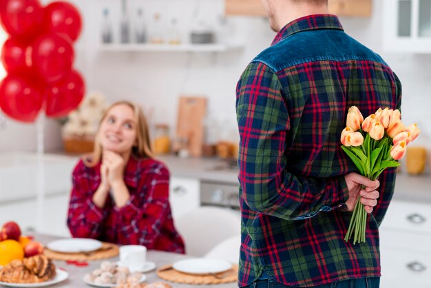 Close-up man surprising woman with flowers