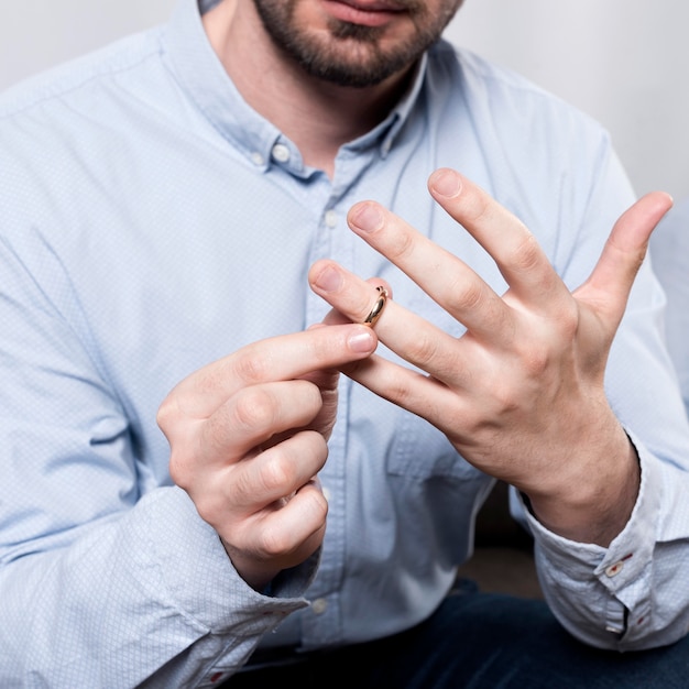 Free Photo close-up man taking wedding ring off finger