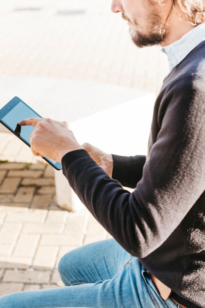 Free photo close-up of man touching the touch screen of smart phone at outdoors