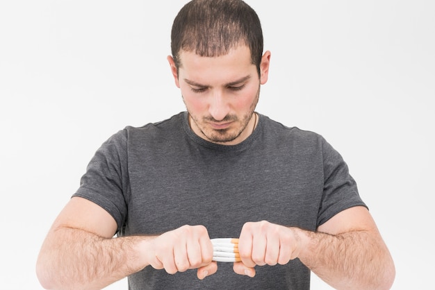 Close-up of a man trying to break the pile of cigarette with hands isolated on white background