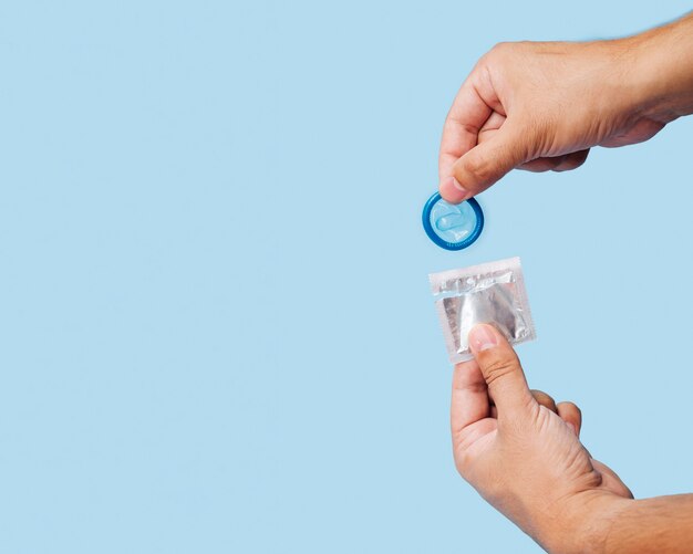 Close-up man unwrapping blue condom