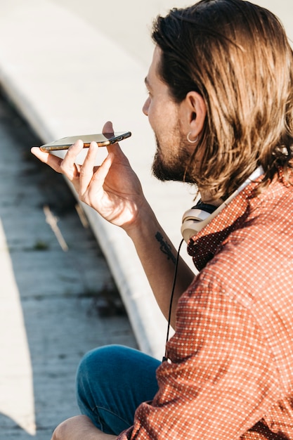 Free photo close-up of a man using smart phone voice recognition on line