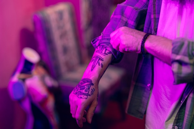 Close-up of a man with tattoo on his hand folding the shirt sleeves