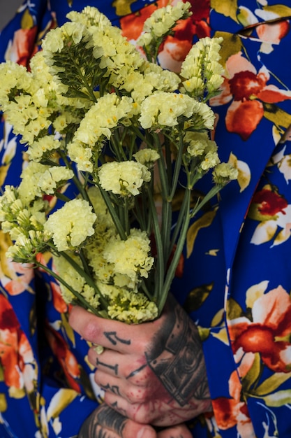 Free Photo close-up of a man with tattoo on his hand holding limonium flower in hand