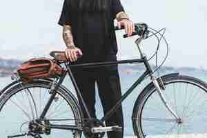 Free photo close-up of a man with tattoo on his hand standing with bicycle