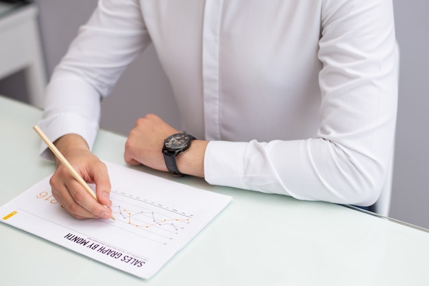 Close-up of manager sitting at table and reading sales report