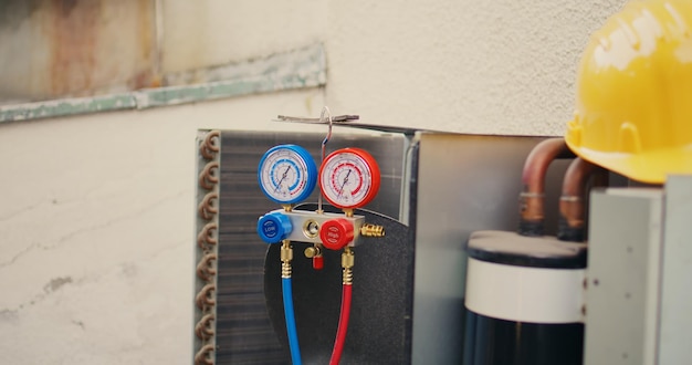 Close up of manifold gauges used for checking air conditioner refrigerant in need of maintenance and protection helmet. Set of barometer high or low freon levels benchmarking hvac system component