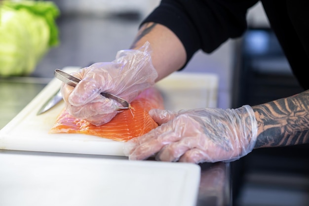 Close up of mans hands cutting fish for sushi