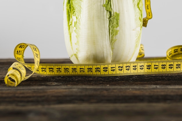 Free Photo close-up of measuring tape and lettuce on wooden surface