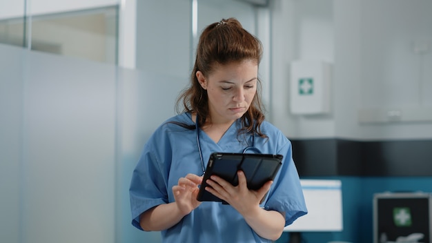 Free photo close up of medical assistant looking at tablet screen with information