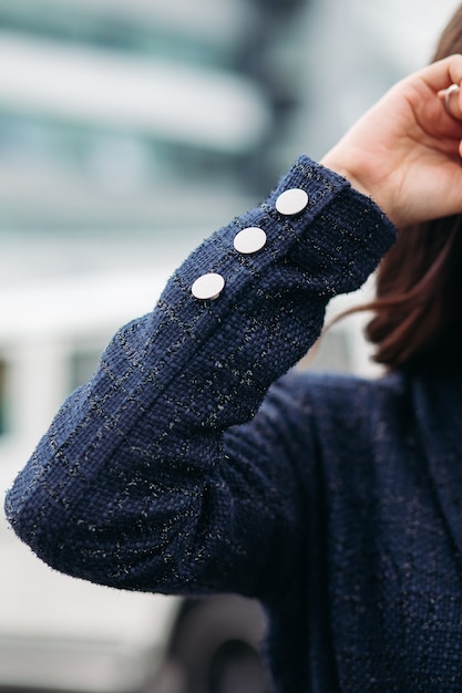 Close up of modern lady in stylish black jacket holding hand up and standing in the city. Copy space