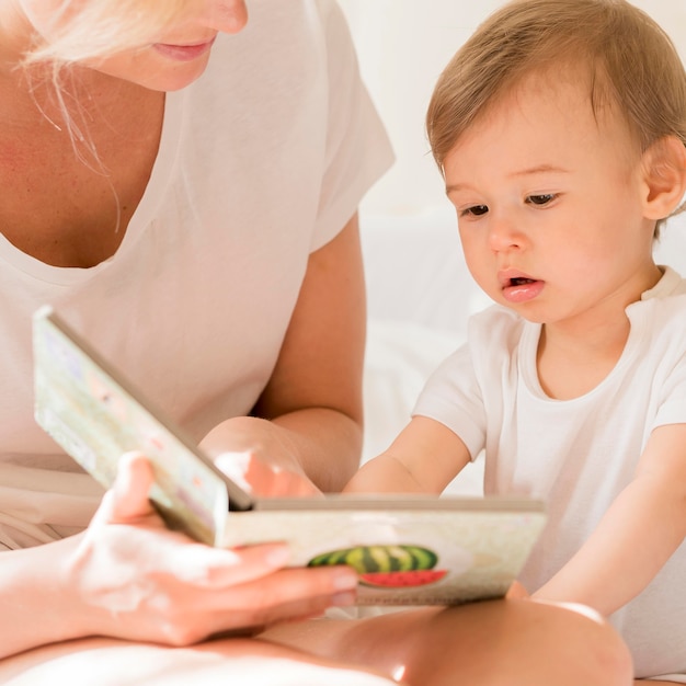 Free photo close-up mom reading to baby in bed