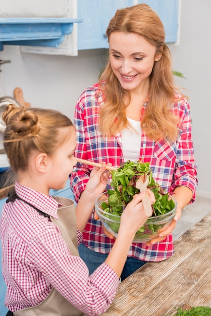 Close-up of mother and daughter preparing the salad