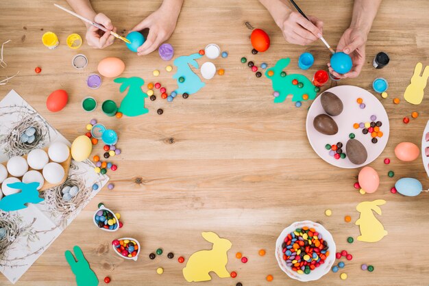 Close-up of mother and daughter's hand painting the eggs with brush on easter day