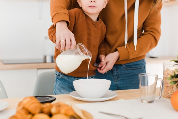 Close-up mother and son pouring milk