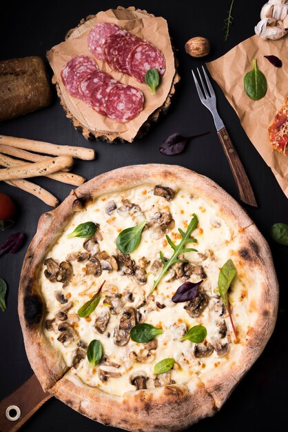 Close-up of mushroom cheese pizza; pepperoni slices; bread sticks and fork on counter