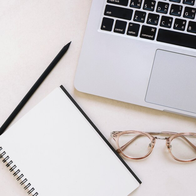 Close-up notebook and glasses near laptop