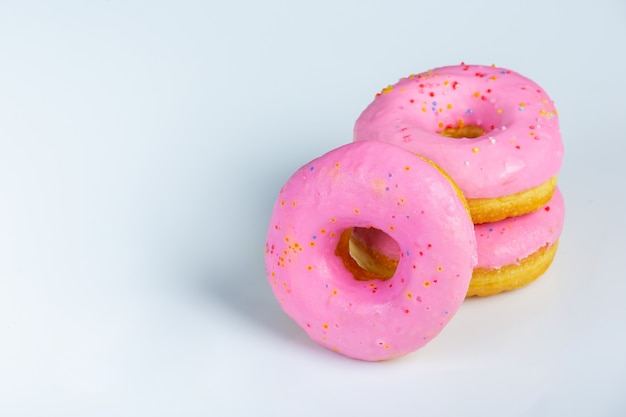 Close-up od pink donuts surves on white wall.