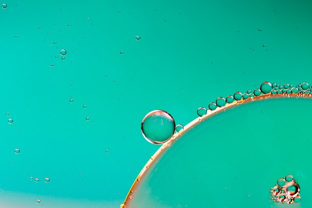 Close-up oily bubbles and droplets in colourful watery backdrop