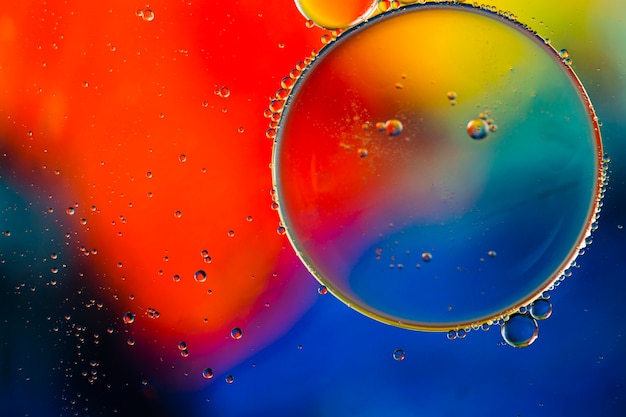 Close-up oily bubbles and droplets in colourful watery backdrop