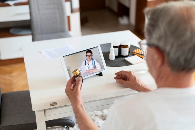 Free photo close up old man talking to online doctor