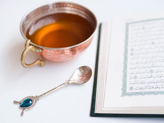 Free photo close up opened quran with tea cup