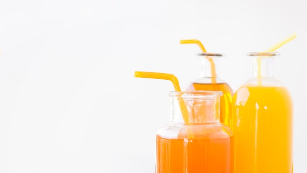 Free Photo close-up of an oranges and mango juice bottles with drinking straws isolated on white background