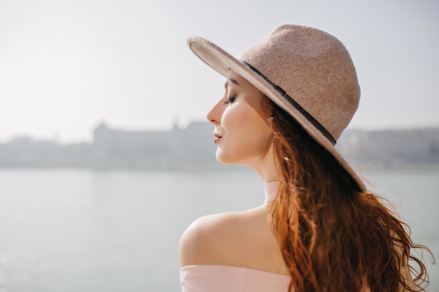 Close-up outdoor portrait of blissful ginger woman enjoying sea breeze