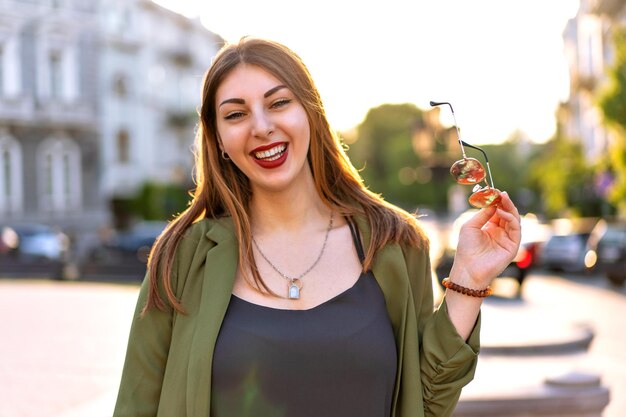 Close up outdoor portrait of pretty stylish woman posing at Europe city, sunny day, elegant outfit and acsessorizes.