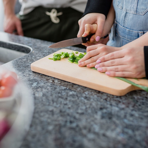 Close-up parents helping girl to cut vegetables