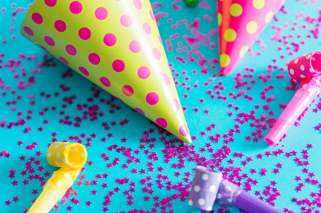 Free photo close-up party horns near hats on confetti