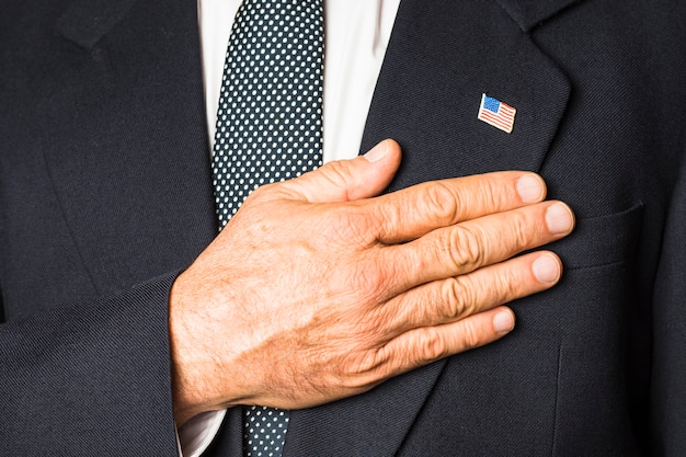 Free photo close-up of a patriotic man with usa badge on his black coat touching hand on his chest