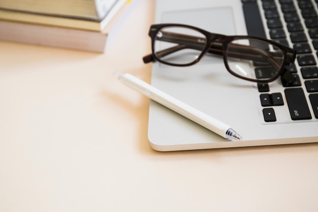 Free Photo close-up of pen and eyeglasses on laptop keypad