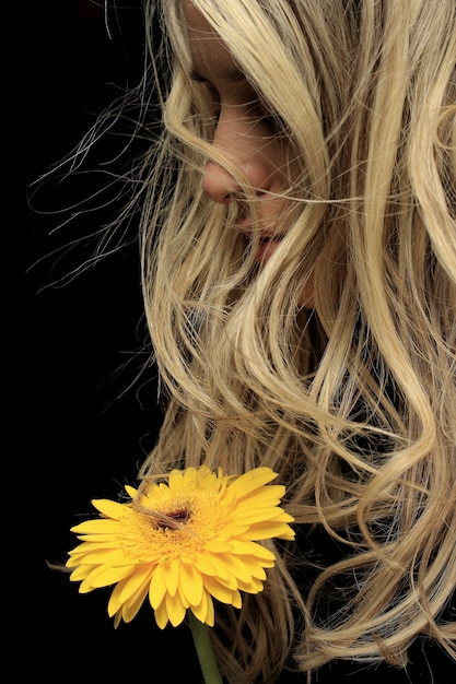 Close-up of pensive woman with yellow flower