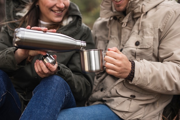 Close-up people with thermos and mug