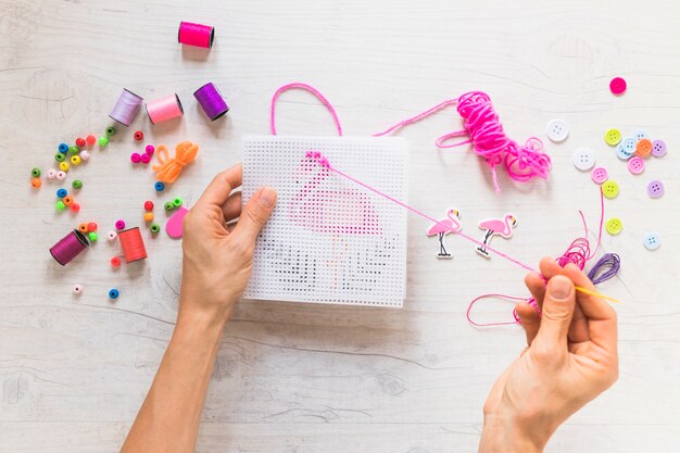 Close-up of a person cross-stitch embroidery with floss thread with decorative elements