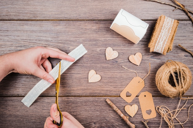 Free photo close-up of a person cutting the lace with knife on wooden desk