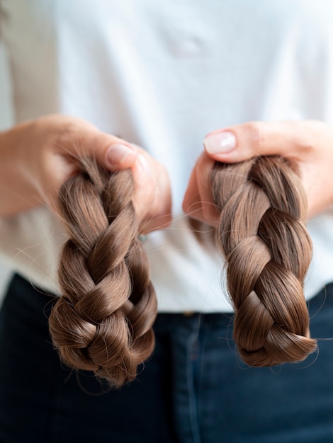 Free photo close-up person holding brown braids