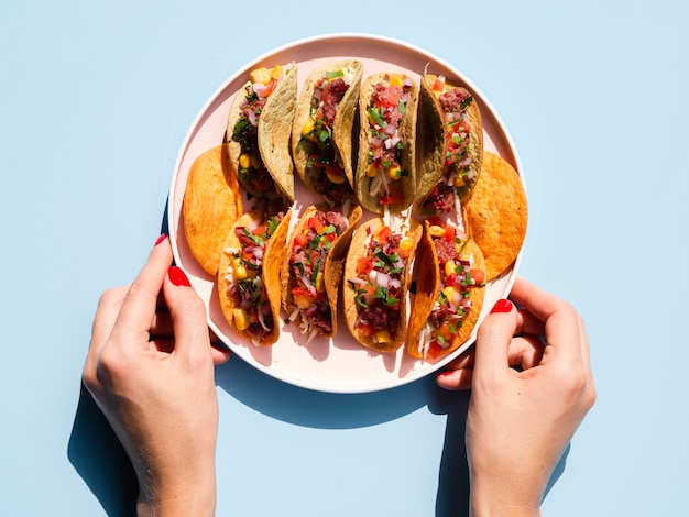 Free Photo close-up person holding plate with tacos