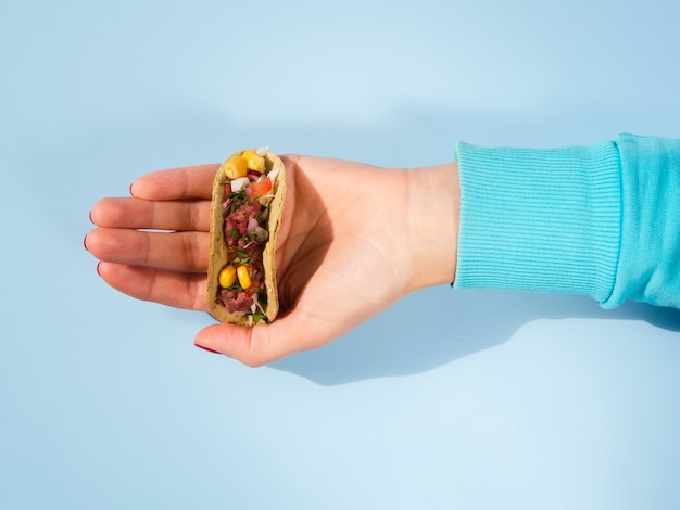 Free photo close-up person holding small taco