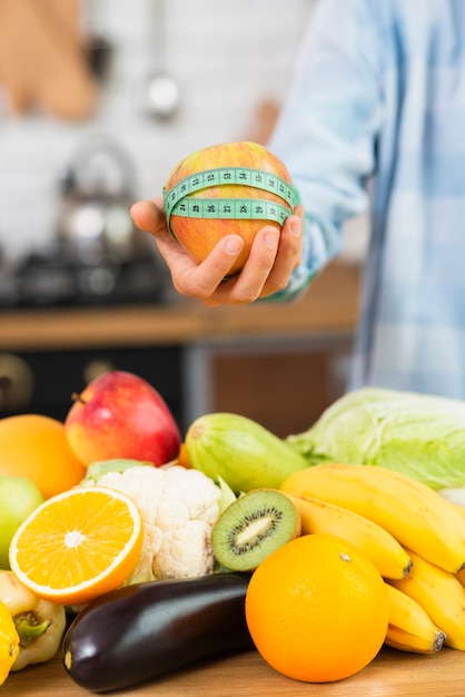 Free Photo close-up person holding up apple and measuring tape