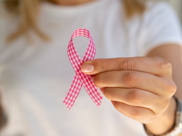 Free Photo close-up person holding up pink and white ribbon