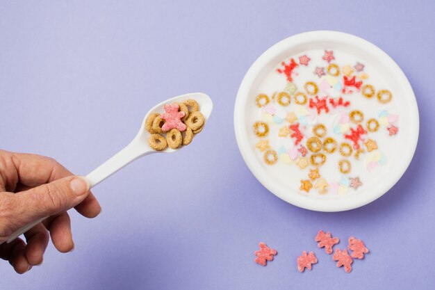 Close-up person holding up spoon with cereals