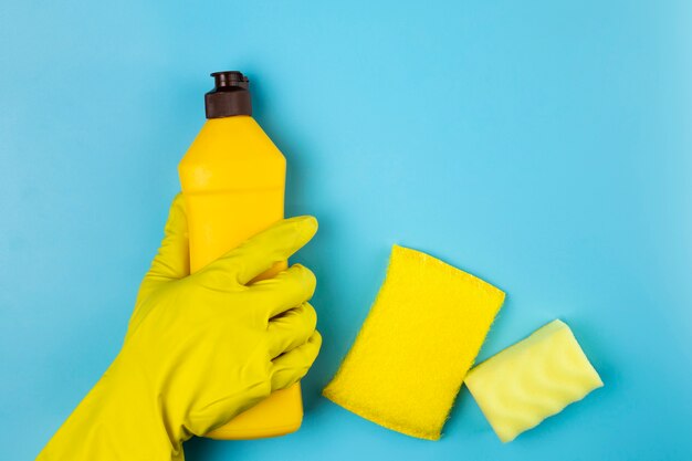 Close-up person holding yellow detergent bottle