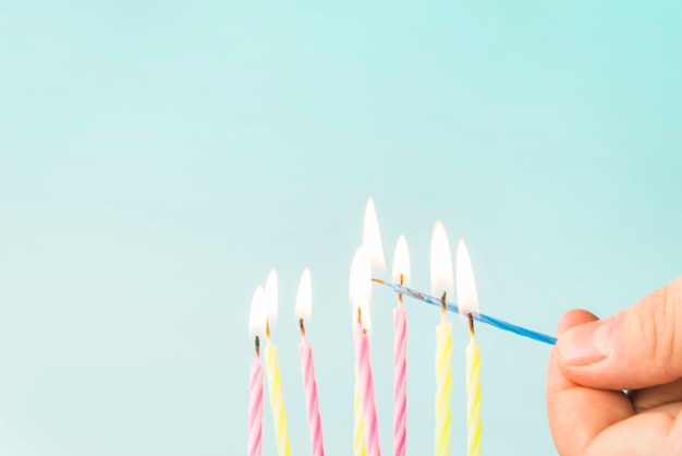 Free photo close-up of a person lightning candles against blue background