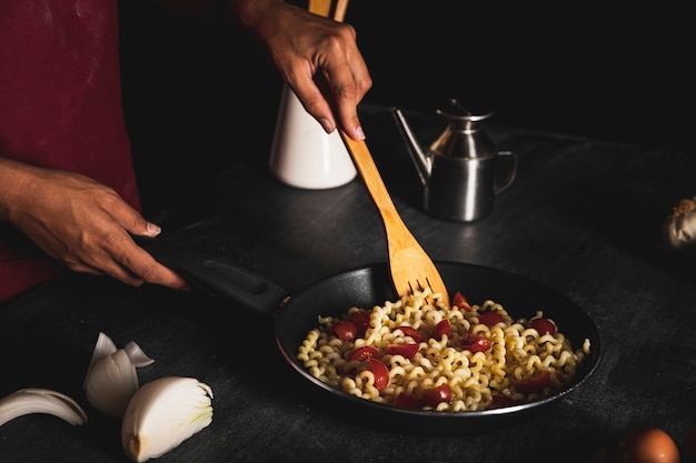 Free Photo close-up person making pasta in pan