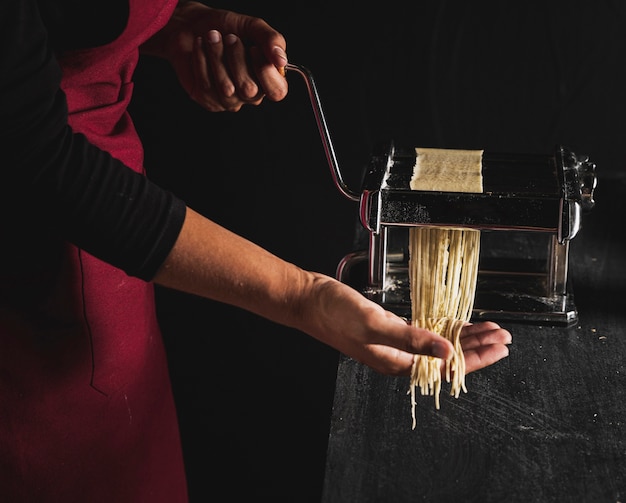 Close-up person making pasta with machine 