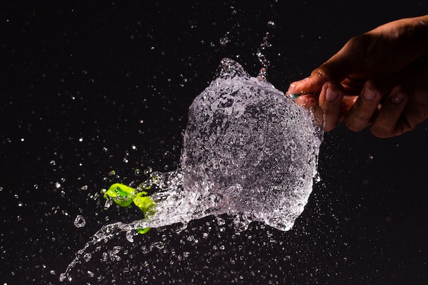 Close-up person popping a water balloon