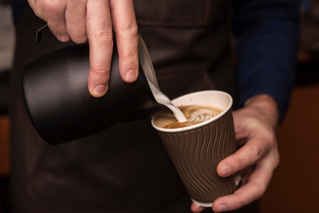 Free photo close-up person pouring milk into coffee cup