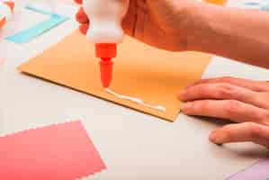 Free photo close-up of a person's hand applying white glue on paper